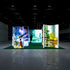 A frontal view of a glowing exhibition stand showcasing nature-inspired designs with images of waterfalls, greenery, and a person caring for plants. The green carpet complements the natural theme, creating an inviting atmosphere.